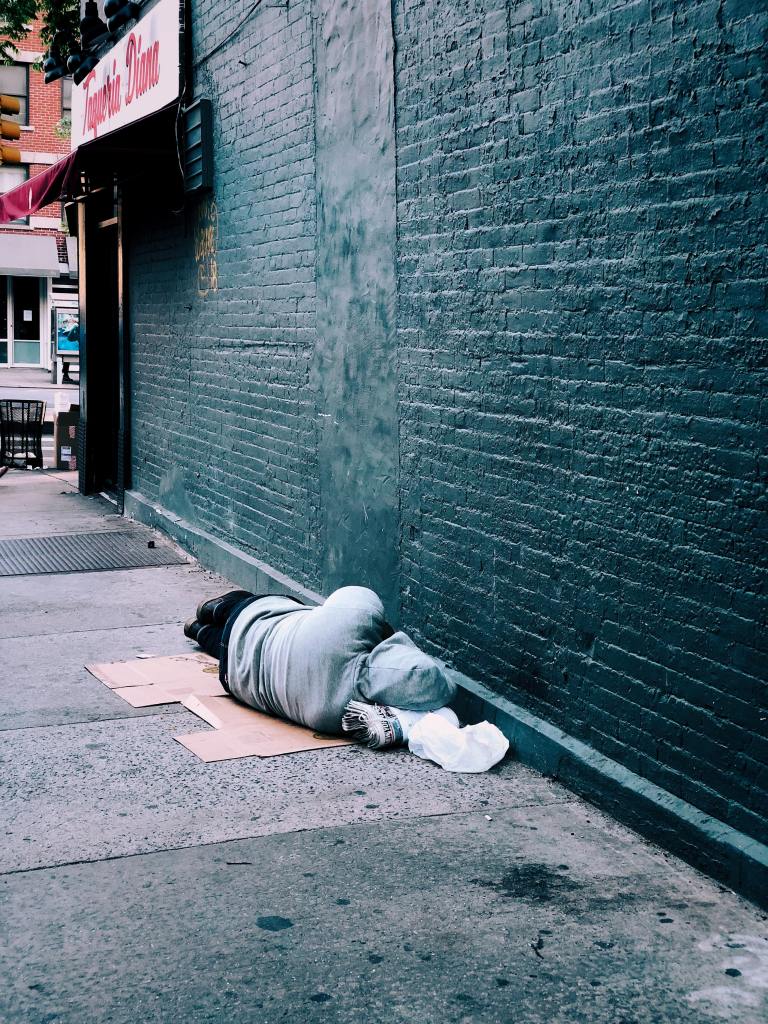 Homeless person sleeps on a cardboard box on the street